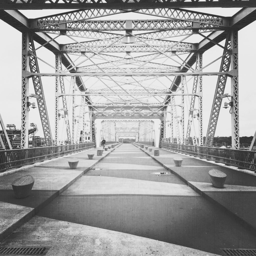 Repeated steel beams frame a truss bridge in Tennessee, making a functional crossing into a strongly symmetrical architectural composition.