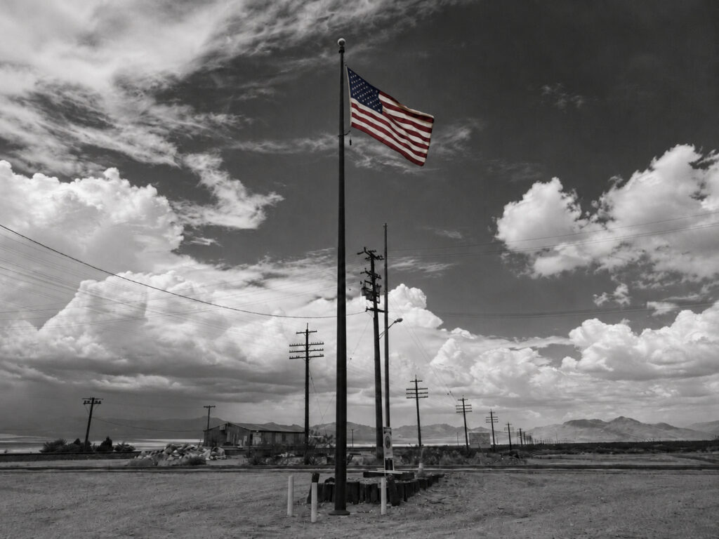 The American flag flies against a broad sky, a national symbol seen here as a physical object exposed to wind and weather.