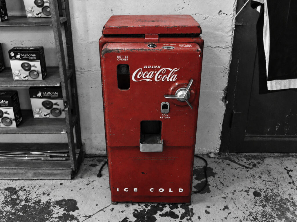 A red Coca-Cola cooler stands as both a practical object and an instantly recognisable example of American commercial branding.