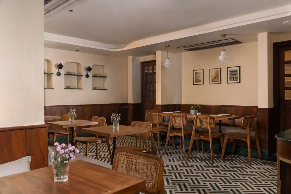Dining area with chequered stone floor and timber furniture at Abode Jaipur
