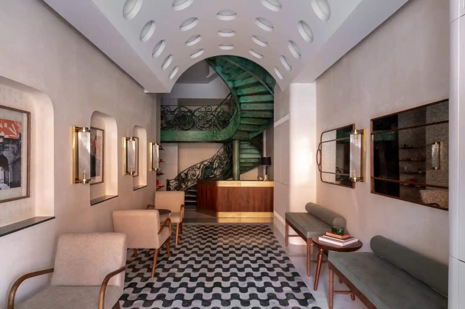 Vaulted entrance corridor at Abode Jaipur, with chequered stone floor and the green spiral staircase beyond