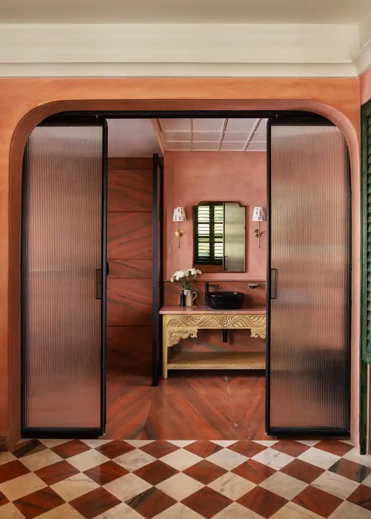 Pink bathroom with fluted glass doors and a carved vanity at Abode Jaipur