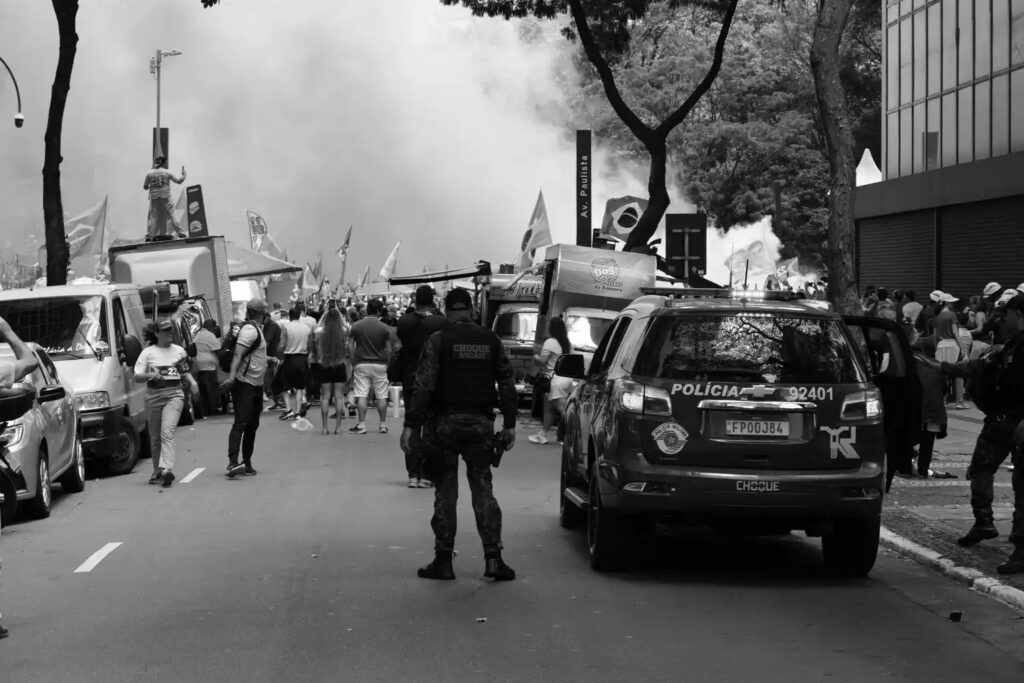 Police personnel and vehicles are visible around the demonstration. The photograph records the public-order presence and changes to ordinary street activity accompanying the event.