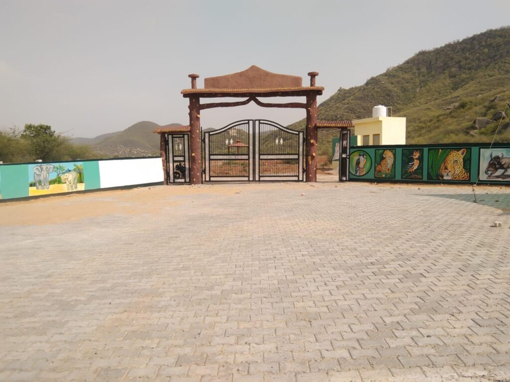 Entrance gate and paved forecourt of the urban forest near Viratnagar, with hills behind