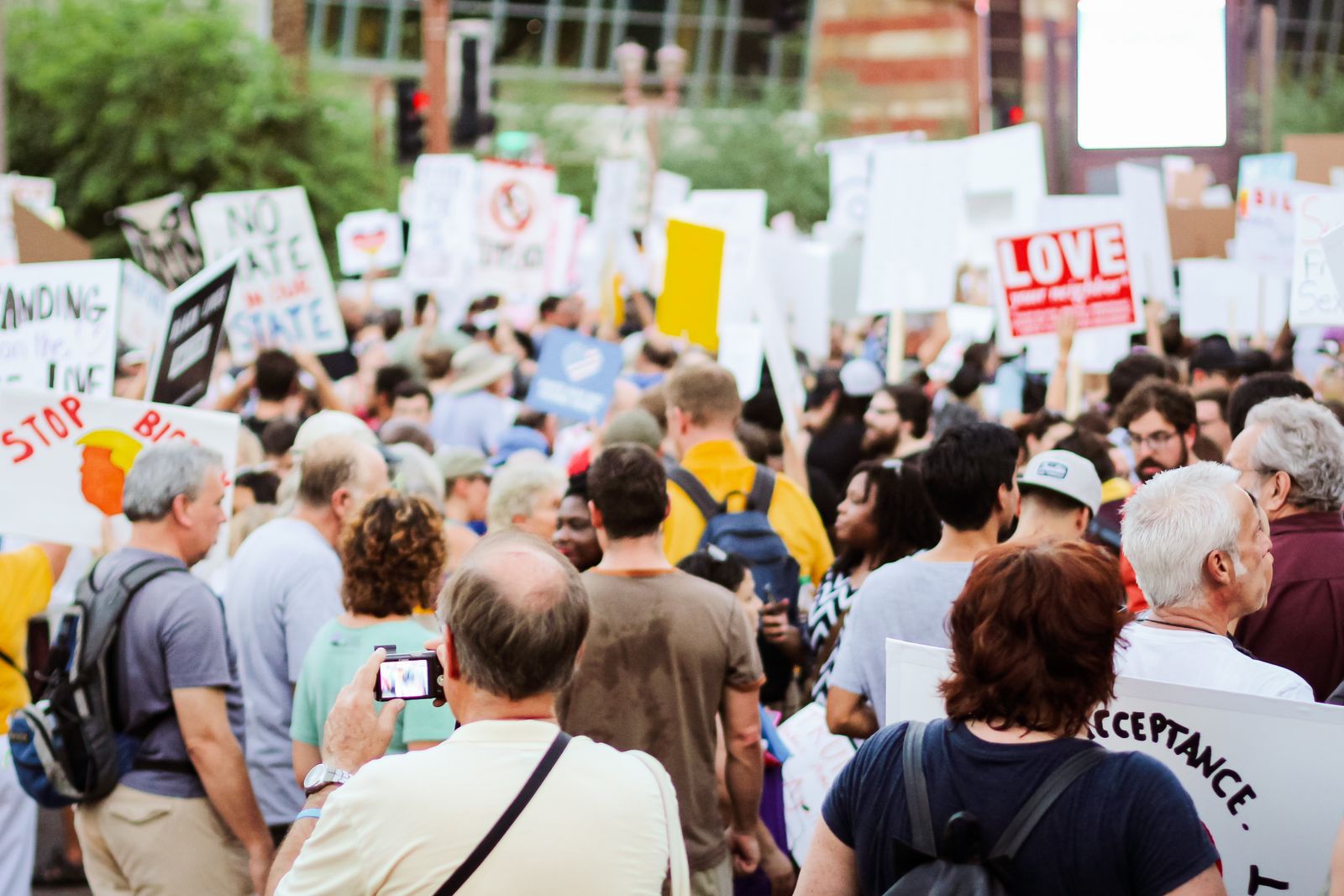 A crowd of protesters seen from behind, holding placards in a city street