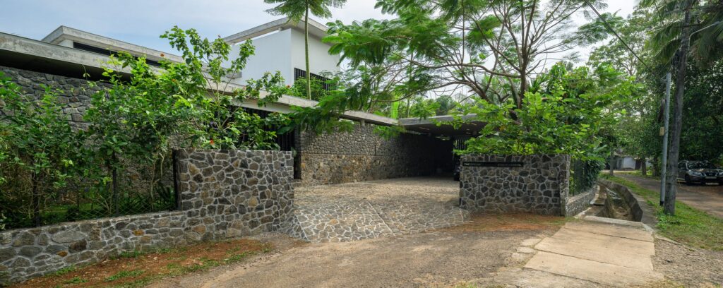 The street face is closed and private, with stone walls and dense planting. Photo: Praveen Mohandas