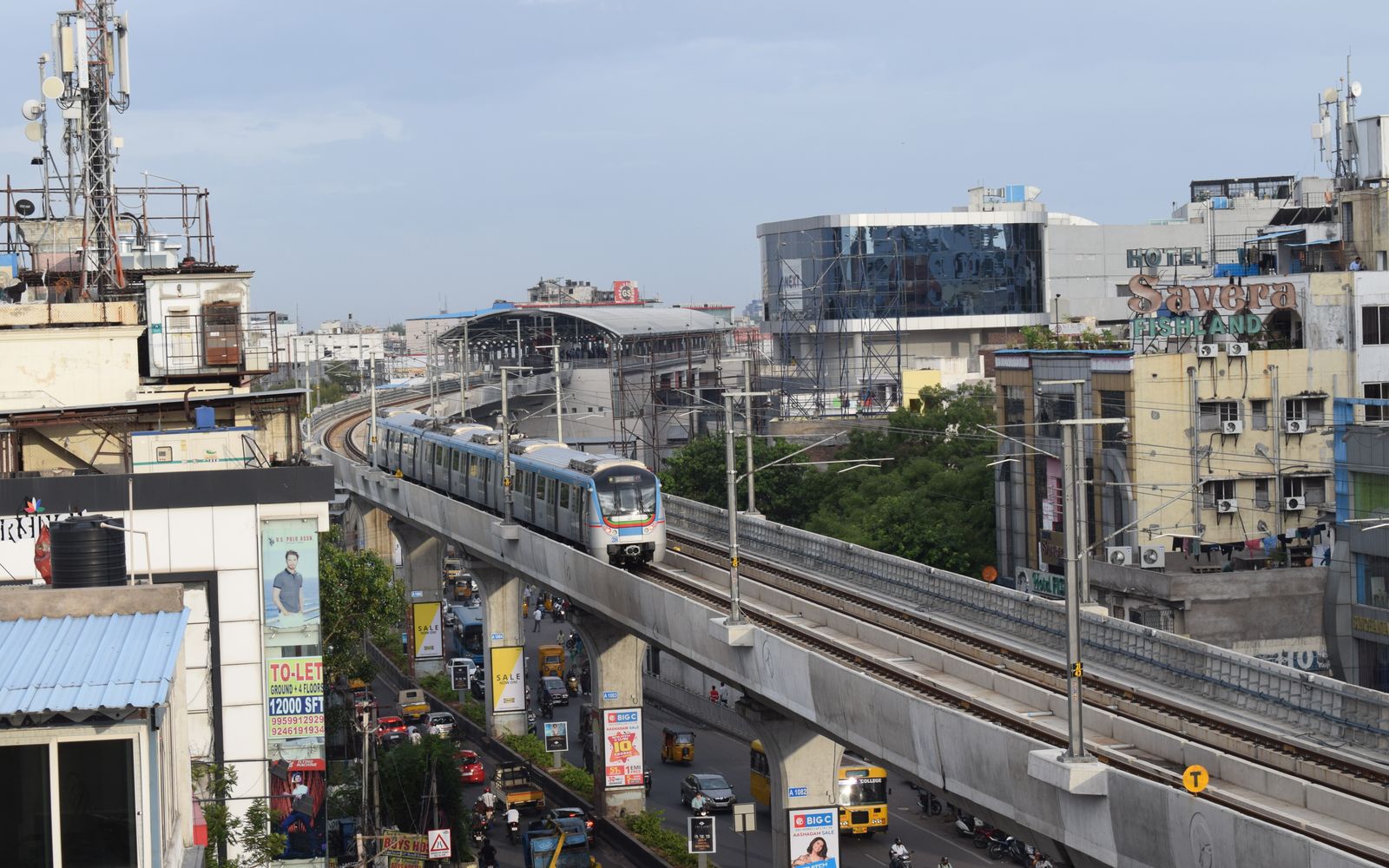 A Hyderabad Metro train on an elevated track above city streets